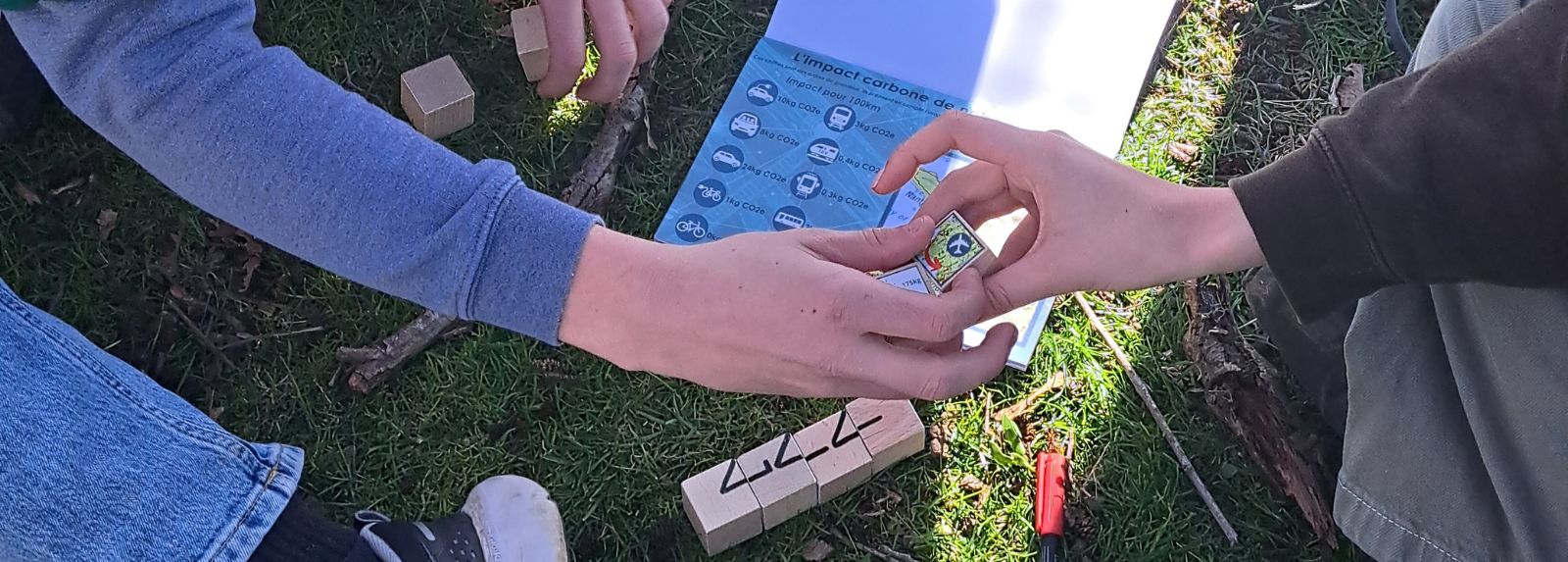 Zoom sur les mains de deux personnes qui manipulent des cubes en bois pour résoudre une énigme sur l'impact carbone des transports.