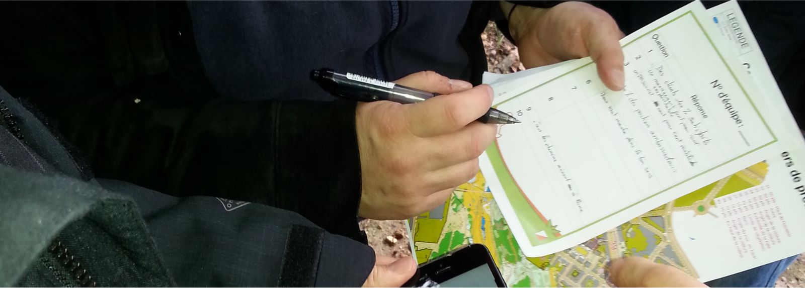 Une équipe en pleine nature, résolvant une énigme de l'orient'SCORE trouvée
      à l'aide d'une carte de course d'orientation.